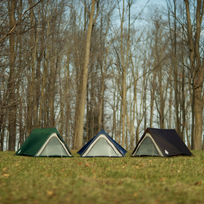 Three fully built Woods A-frame 3-person 3-season tents in green, navy, and brown on grass