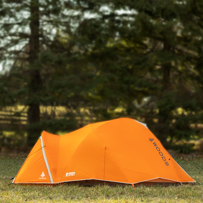Side view of a fully built Woods Pinnacle Lightweight 4-Person 4-Season Tent on grassy campground