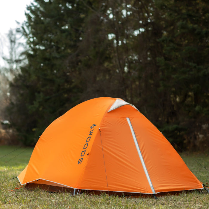 Back view of a Woods Pinnacle Lightweight 4-Person 4-Season Tent on grassy campground