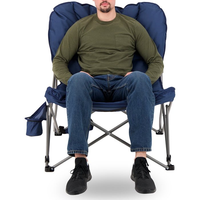 A man sitting on the Woods Mammoth Folding Padded Camping Chair in Navy