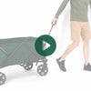 A man rolling the Woods Outdoor Collapsible Utility King Wagon in Green