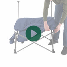 Load image into Gallery viewer, A person setting up the Woods Mammoth Folding Padded Camping Chair in Navy