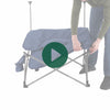 A person setting up the Woods Mammoth Folding Padded Camping Chair in Navy