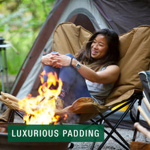 Load image into Gallery viewer, A woman sitting on the Woods Mammoth Folding Padded Camping Chair in Dijon around a campfire on campground