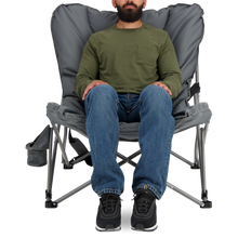 Load image into Gallery viewer, A person sitting on the Woods Mammoth Folding Padded Camping Chair in color Gun Metal from the front