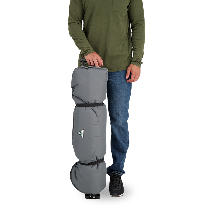 A person standing next to a rolled up Woods Mammoth Folding Padded Camping Chair in color Gun Metal