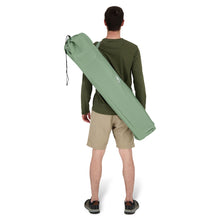 Load image into Gallery viewer, Behind view of a person carrying the Woods Siesta Folding Reclining Padded Camping Chair in Sea Spray inside carry bag across their back