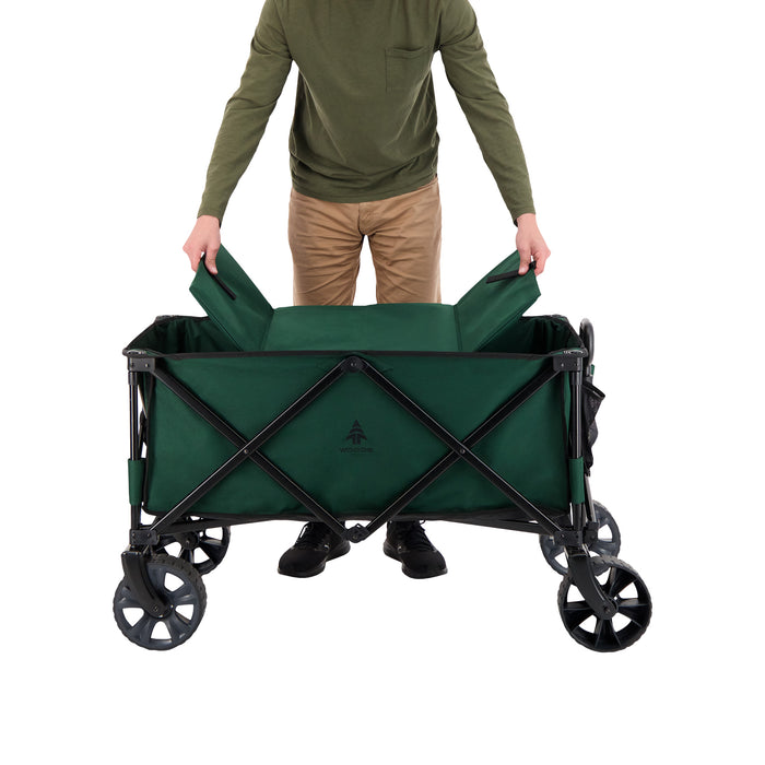 A person putting in the base of the Woods Outdoor Collapsible Utility King Wagon in Green