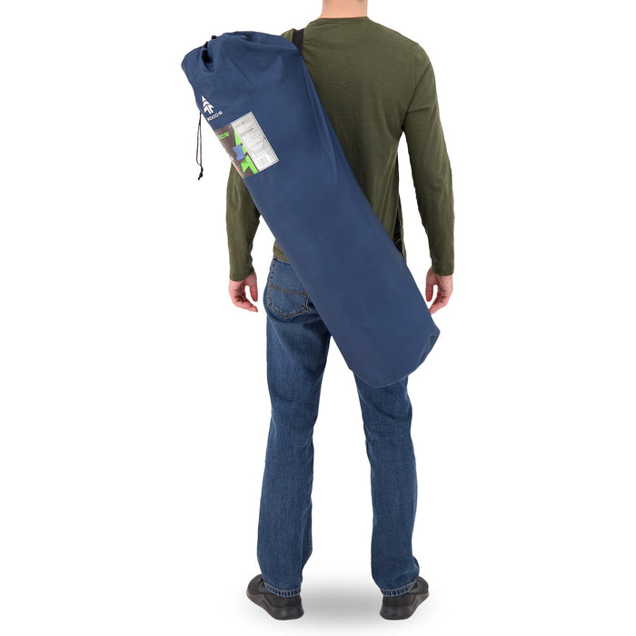 Behind view of a person carrying the Woods Mammoth Folding Padded Camping Chair in Navy inside a carry bag across their back