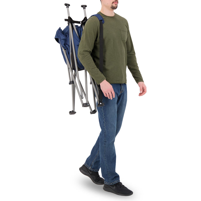 A man carrying the Woods Mammoth Folding Padded Camping Chair in Navy across their back without carry bag 