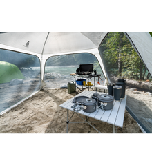 Load image into Gallery viewer, Various cookware and camping tables set up under the Woods Easy Setup Canopy Camping Screen House on campground