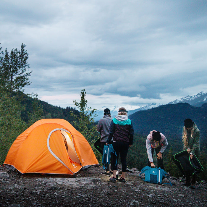 Four people standing next to a Woods Pinnacle Lightweight 4-Person 4-Season Tent overlooking the mountains