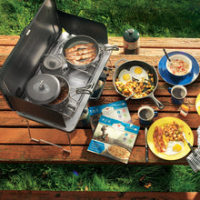Load image into Gallery viewer, Food being cooked on the Woods Selkirk Anodized 4-piece Camping Cook Set on top of a portable stove and camping table